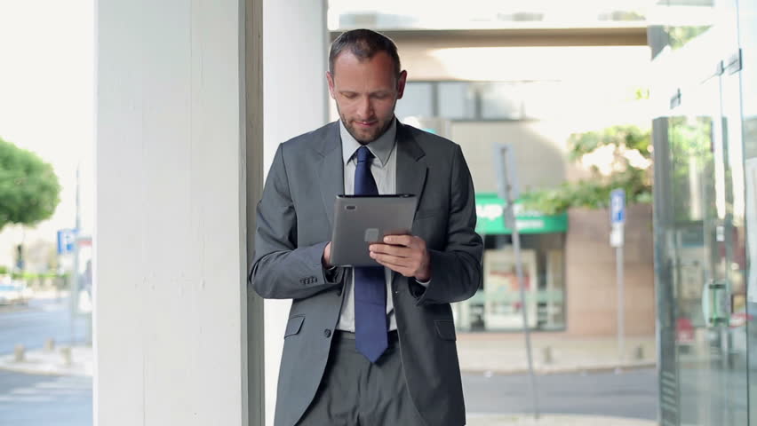 Happy businessman with tablet computer in the city
