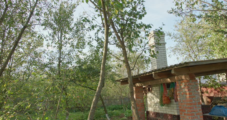 Old brick barbecue grill with a chimney standing in a lush green garden on a sunny day