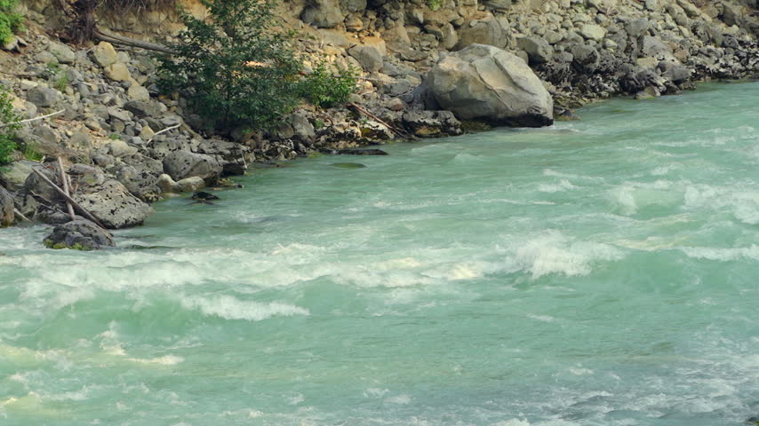 Turquoise River Rapids Flowing Past a Rocky Shore