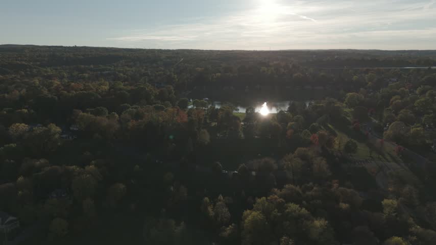 Forest Sunset- Aerial view over an autumn forest toward a lake at sunset.