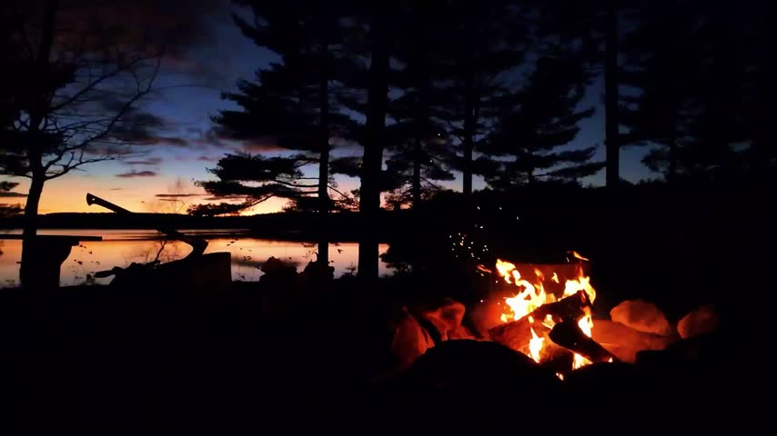 Camp fire on lake at dusk