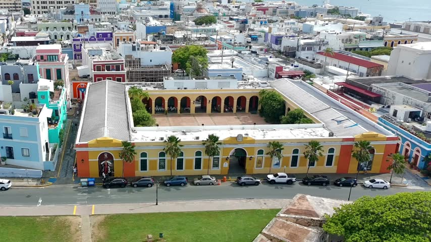 Drone pan video showing some of the colorful homes and buildings at old San Juan, Puerto Rico along with the road heading towards el Morro castle. 