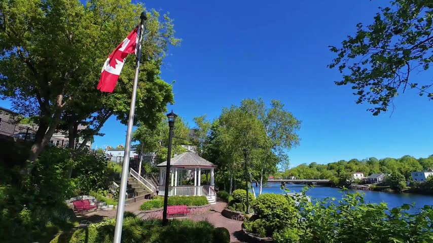 Small town public garden along a river with Canadian flag