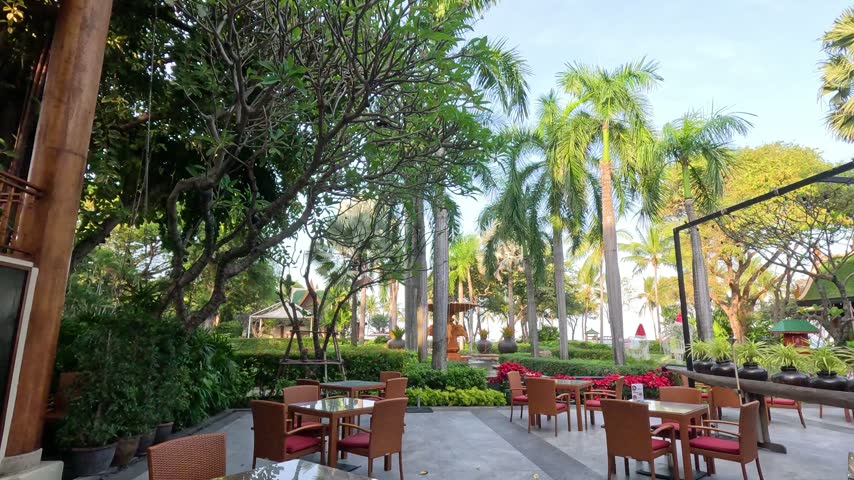 Empty tables in garden cafe, tropical landscape with palm trees and water fountain, outdoor dining space, summer vibes.