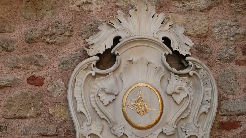 Beautiful antique marble drinking fountain in Istanbul, featuring Ottoman design, Arabic calligraphy, carved details and a warm textured brick background