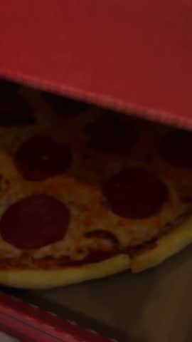 Freshly baked pepperoni pizza sitting inside an open cardboard box on a marble table. Hot takeaway meal with melted cheese and salami
