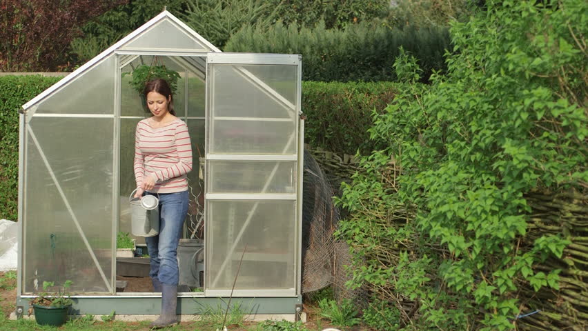 Young woman gardening outside greenhouse