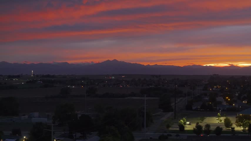 Greeley Colorado sunset with orange and purple clouds and the front range rocky mountains silhouetted in the background.