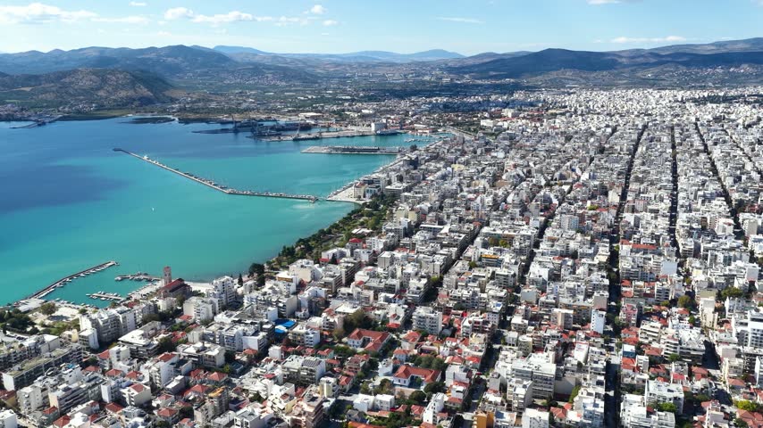 Establlishing aerial view of the city of Volos, Magnesia, Greece, with residential districts at the waterfront until the port during a sunny day