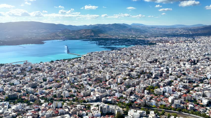 Establlishing aerial view of the city of Volos, Magnesia, Greece, with residential districts until the port and waterfront during a sunny day