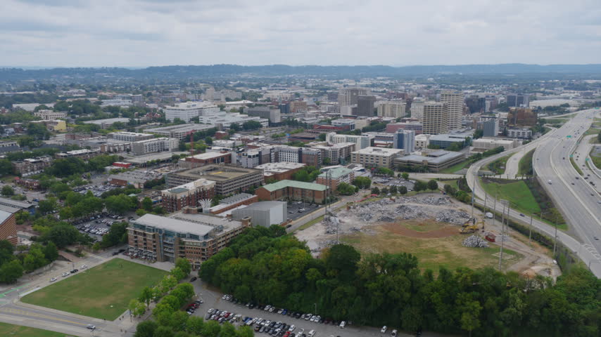 Wide aerial of downtown Chattanooga, Tennessee, with the demolished Lookouts stadium site in the foreground and the city skyline stretching toward distant ridges.