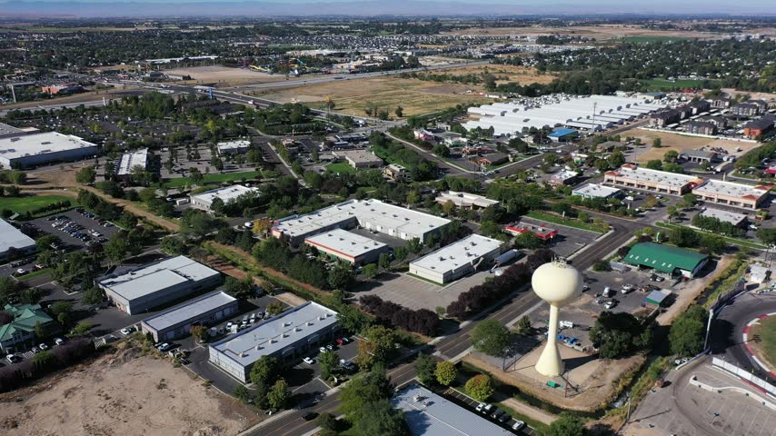 High aerial drone view of Meridian, Idaho with the water tower, rooftops, streets and trees stretching to the horizon.