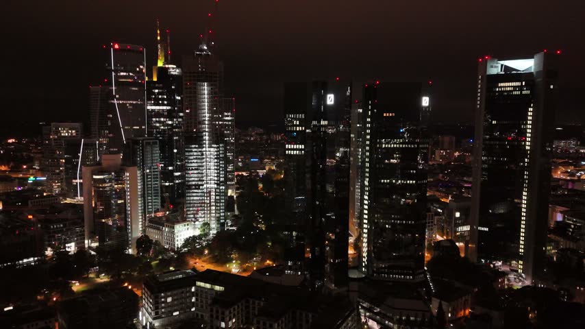 Aerial view of the illuminated skyscrapers and modern office towers of the financial district in Frankfurt am Main, Hessen, Germany.