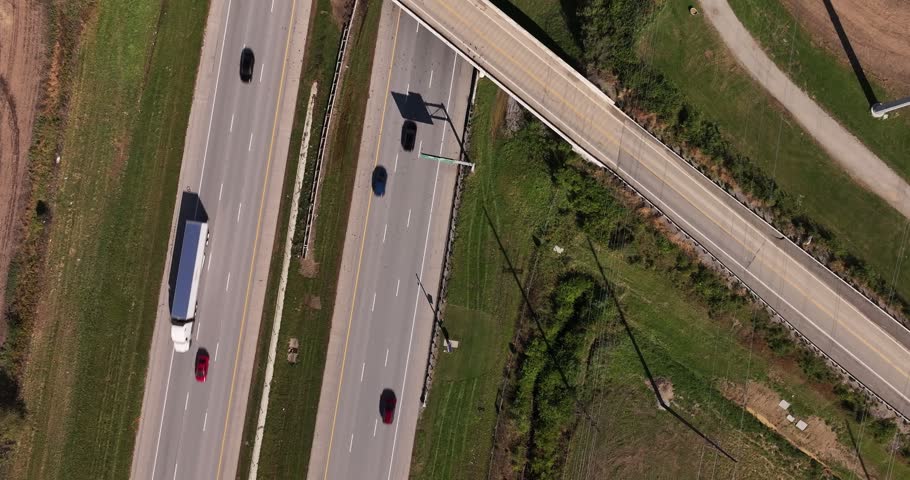 Aerial view of a highway with cars driving under an overpass surrounded by grassy fields in Washington Court House, Ohio, United States.