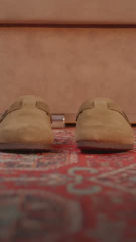 Close up shot of a man stepping feet into comfortable orthopedic home slippers for proper arch support.