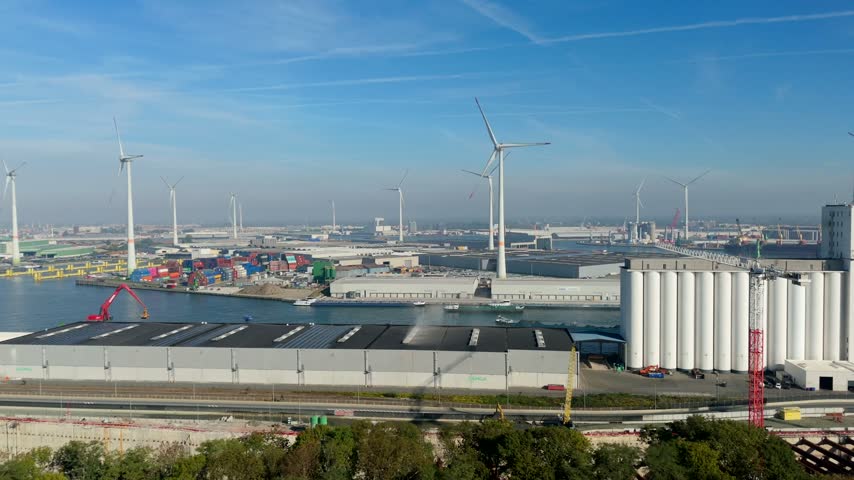 Aerial view Antwerp port with wind turbines, industrial warehouses and shipping containers