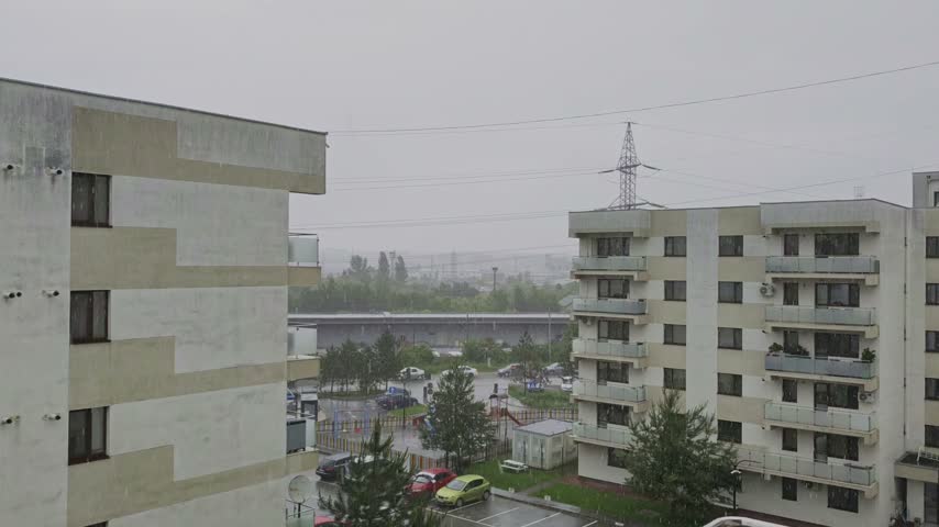 Heavy hailstorm with loud pounding ice rain sounds, captured from an apartment balcony in a residential neighborhood. Dramatic weather video.