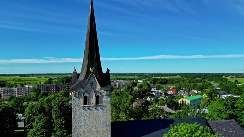 Aerial view of a historic church steeple rising above a lush green town in Estonia.