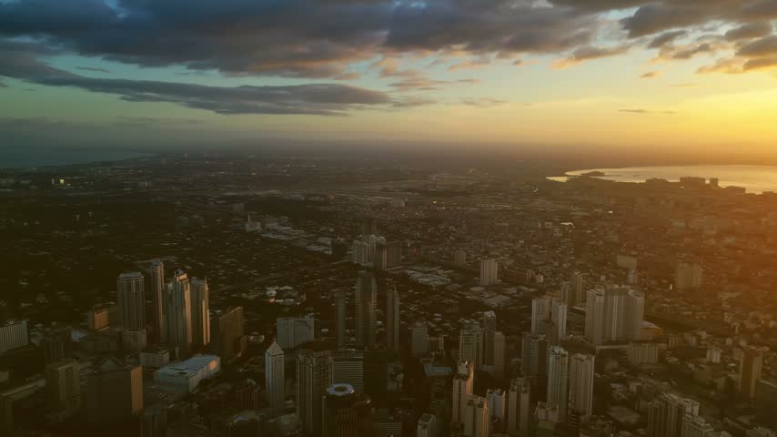 Aerial view of the Manila skyline at sunset with tall buildings and coastal views in Manila, Metro Manila, Philippines.