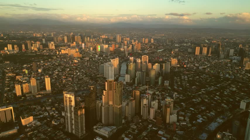 Aerial view of the Manila skyline at sunset, featuring dense urban development, skyscrapers, and the Pasig River winding through the city in Manila, Metro Manila, Philippines.