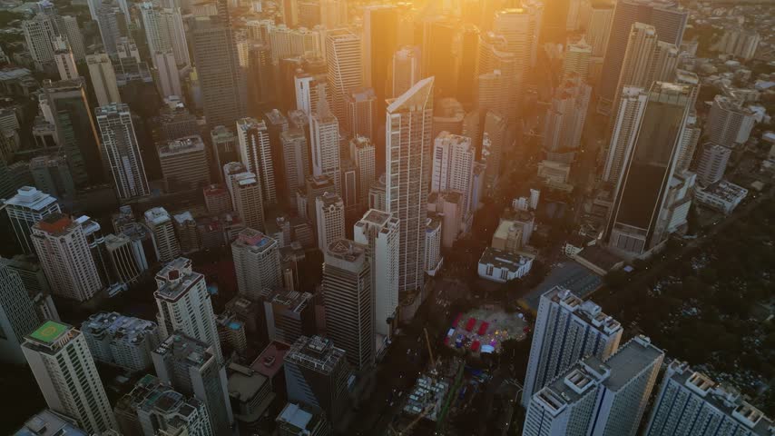 Aerial view of the dense Manila skyline with modern skyscrapers and glowing sunset light over the urban landscape in Manila, Metro Manila, Philippines.