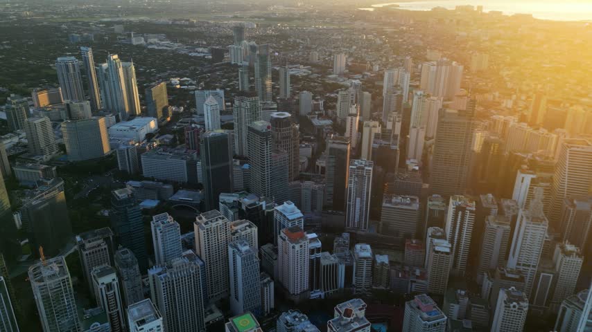 Aerial view of Manila skyscrapers bathed in golden sunset light with dense urban architecture and high-rise buildings in Manila, Metro Manila, Philippines.
