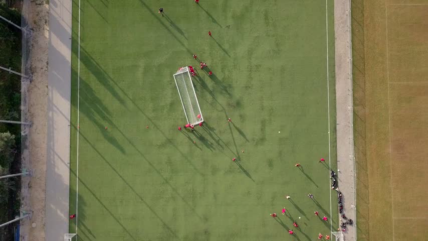 Aerial view of a soccer match on a green pitch with players in red jerseys moving across the field in Israel.