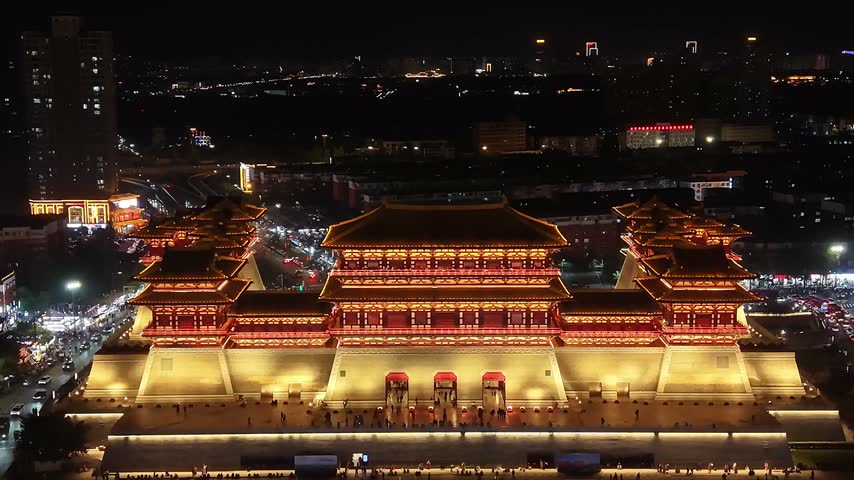 A frontal view of the illuminated Yingtianmen gate at night, with its three gateways, red pillars and golden walls slowly filling the frame.