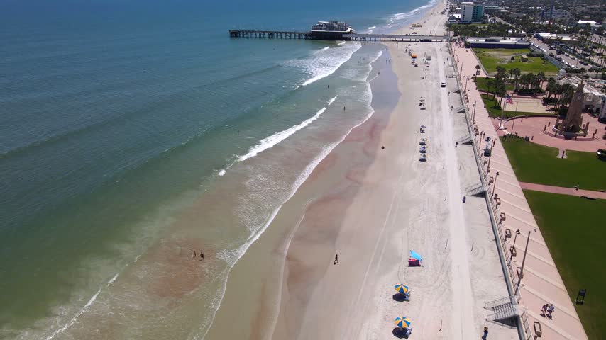 Stairs connect the promenade with the sandy beach beside Daytona Beach ocean waves.