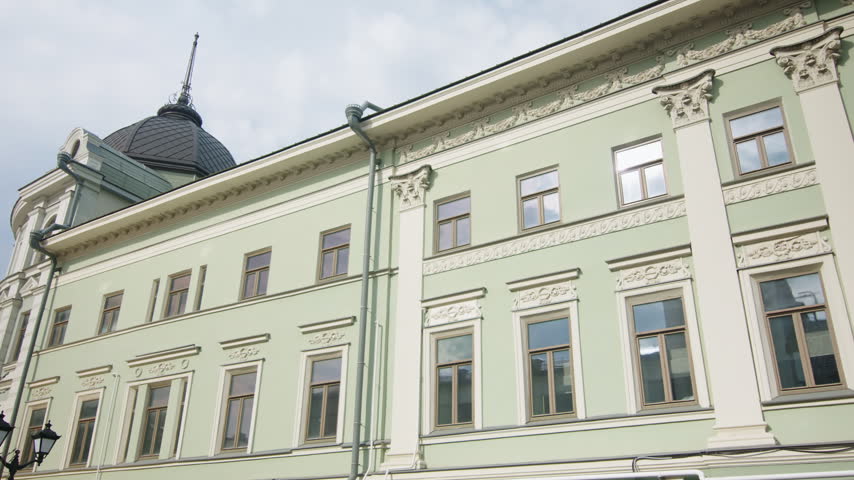 Elegant old building with light green facade and stucco ornaments in town center. Unforgettable architectural heritage in urban area
