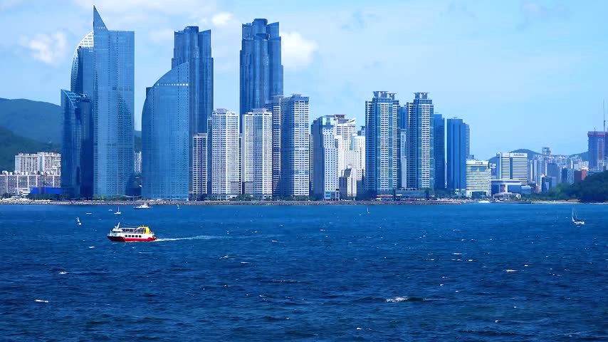 A horizontal video footage capturing the modern skyscraper skyline of Marine City and a cruise ship sailing across the deep blue ocean viewed from Igidae Coastal Walk in Busan.