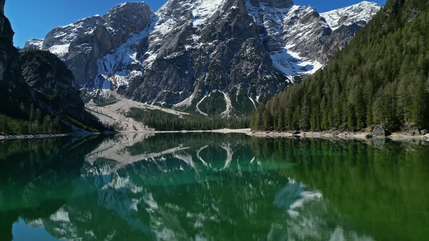 Aerial view of Pragser Wildsee reflecting the surrounding Dolomites mountains and dense pine forests in Prags, Trentino-Alto Adige, Italy.
