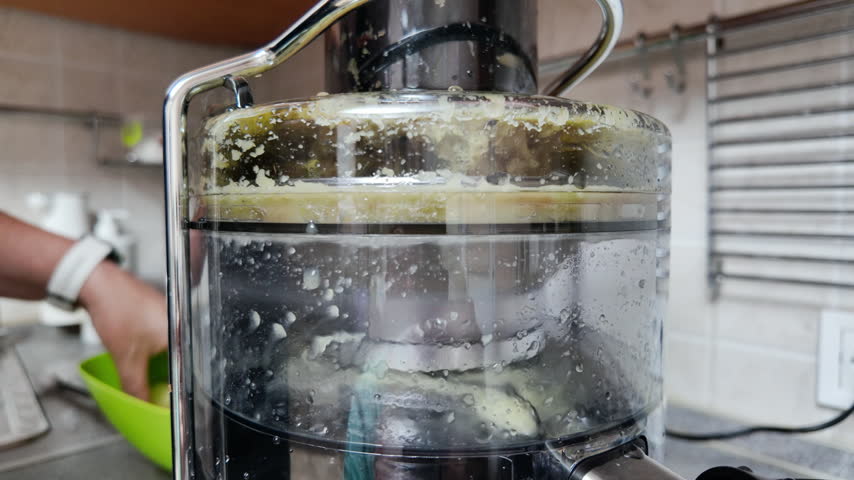 Electric juicer extracting fresh green apple juice on kitchen countertop for healthy lifestyle