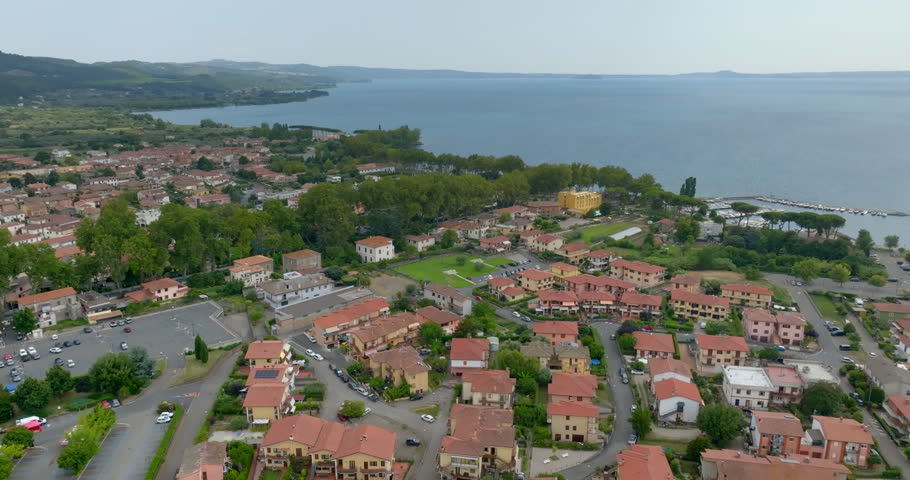 Aerial view of the residential neighborhoods of Bolsena with red tiled roofs and gardens leading down to the shore of Lake Bolsena, in the province of Viterbo, Lazio, Italy. Houses in the foreground.