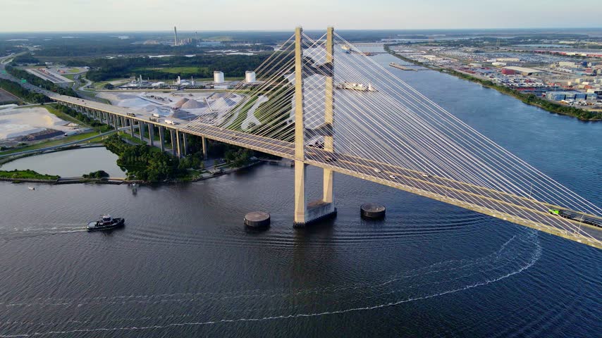 Road transport crosses a cable bridge beside cranes at the Jacksonville port.