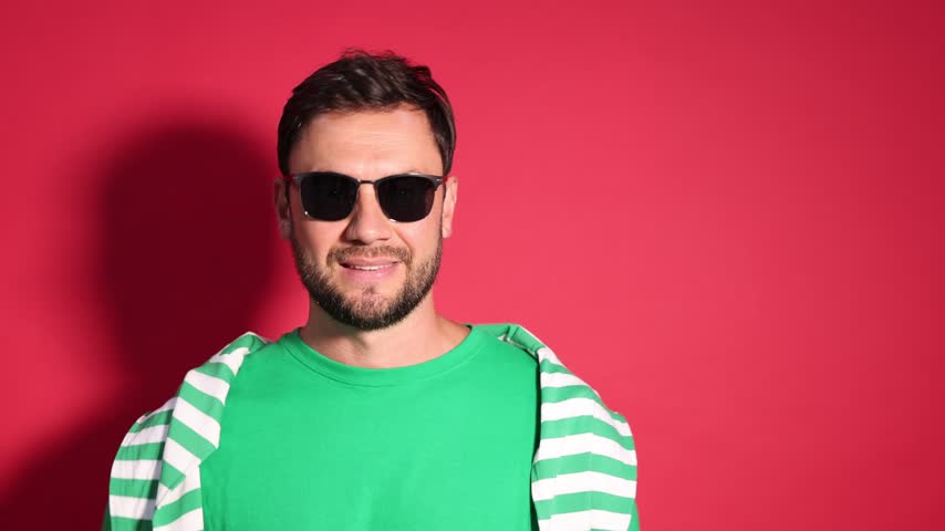 Handsome man in sunglasses against red background