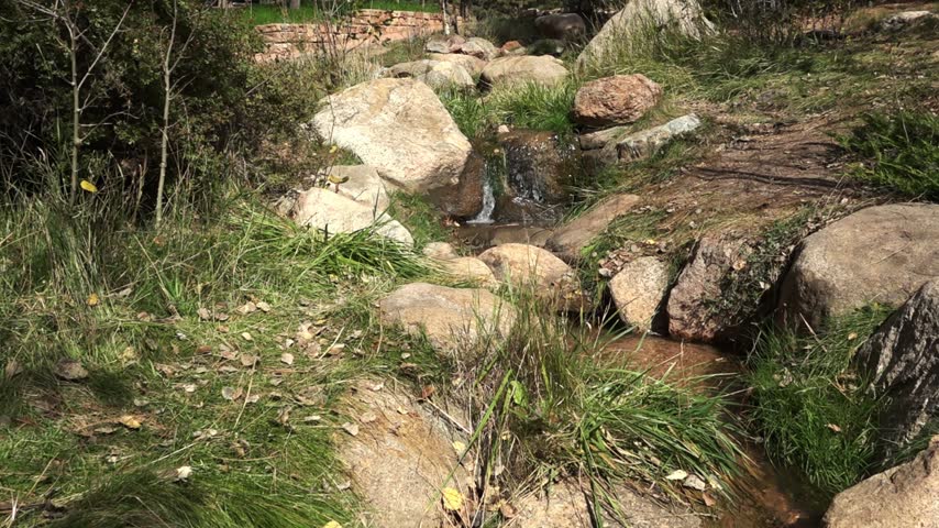 Small Colorado Stream Trickling out of Mountains 4K Loop features a small stream of water running down a hill over rocks in Colorado in a loop.