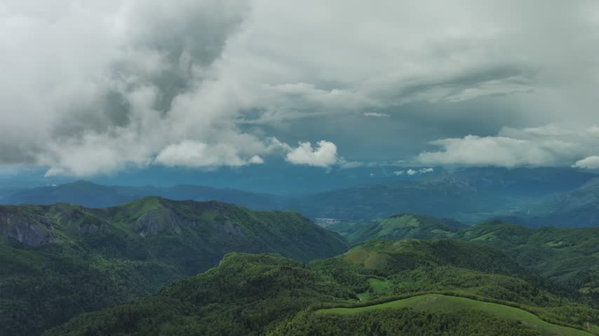 Aerial view of lush green mountains under a dramatic cloudy sky in Montenegro.