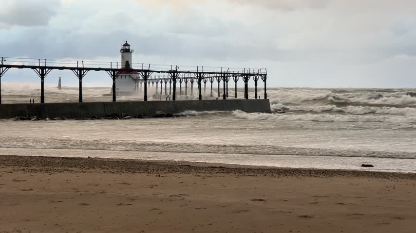 Lake Michigan Gale Force Storm with waves crashing violently against a historic pier and lighthouse during an intense autumn gale in Michigan City, IN USA 
