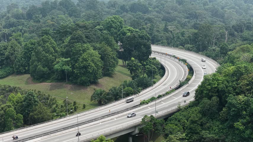 Aerial view of a curved highway winding through lush green forest in Singapore, Singapore.