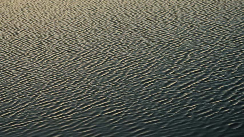 Close-up of river water ripples and sun reflections at dusk.