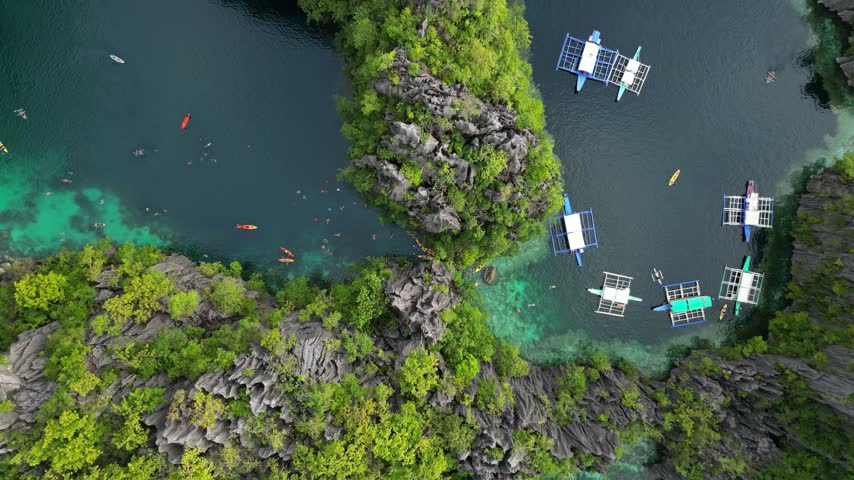 Aerial view of Big Lagoon in El Nido with turquoise water, limestone cliffs, and traditional outrigger boats floating in the Philippines.