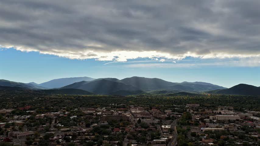 Aerial view of dramatic sun rays shimmering over the foothills of Santa Fe with morning light illuminating the urban landscape of Santa Fe, New Mexico, United States.