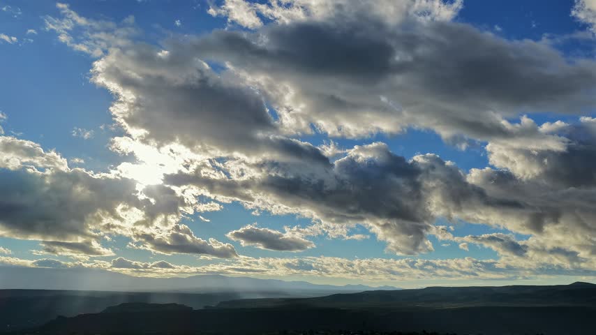 Aerial view of fast moving clouds over a sunlit canyon landscape in White Rock, New Mexico, United States.