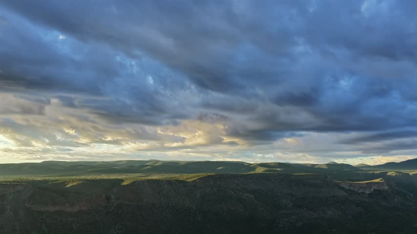 Aerial view of dramatic glowing morning clouds over an emerald canyon valley in White Rock, New Mexico, United States.