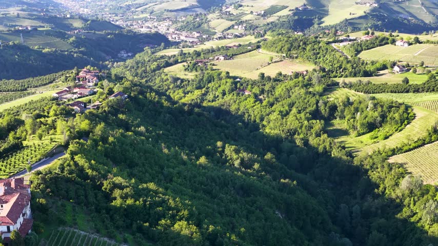 High angle panoramic view over lush rolling green hills and rural landscapes in Piedmont, Italy.