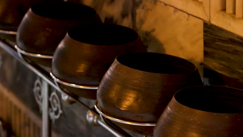 Rows of traditional bronze monk alms bowls arranged for merit making in Wat Pho, Bangkok.