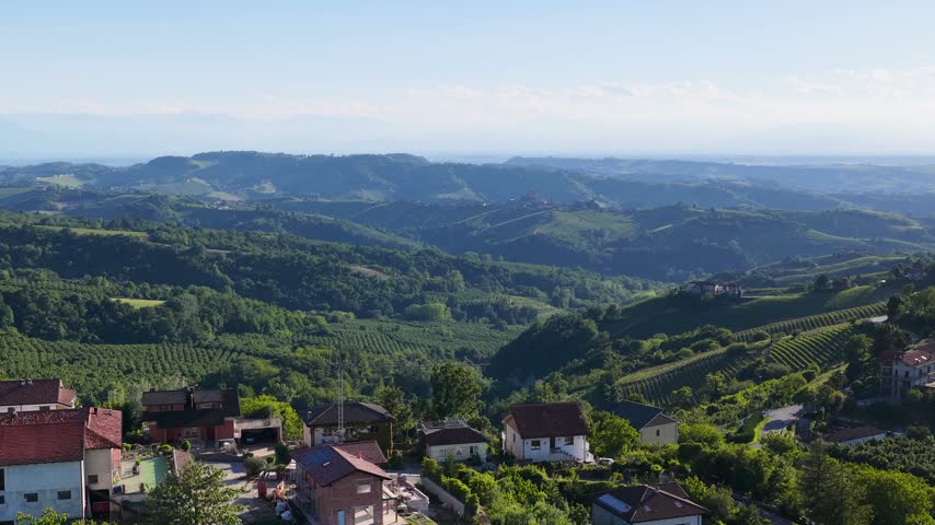 High angle panoramic view over rolling green vineyards and rural hillsides in Piedmont, Italy.