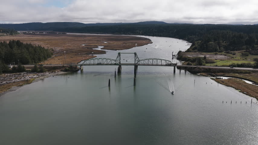 Recreational fishing boat emerges from under Bullards Bridge on the Coquille River near Bandon, Oregon, as the drone ascends