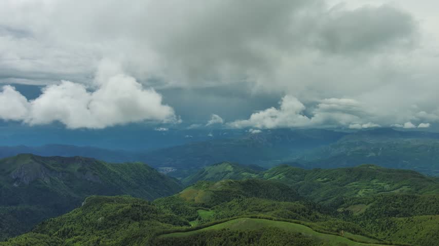 Aerial view of lush green mountains under a dramatic cloudy sky in the highlands of Montenegro.